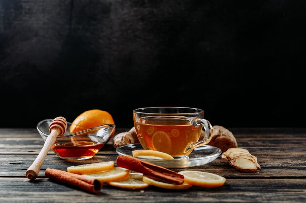 生姜、蜂蜜、乾燥シナモン、暗い木製と黒の背景、側面図でお茶とレモン。テキストのためのスペース