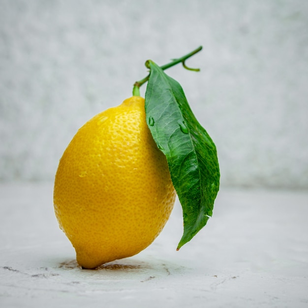 Некоторый лимон со своими лист на белой текстурированной предпосылке, взгляде со стороны.