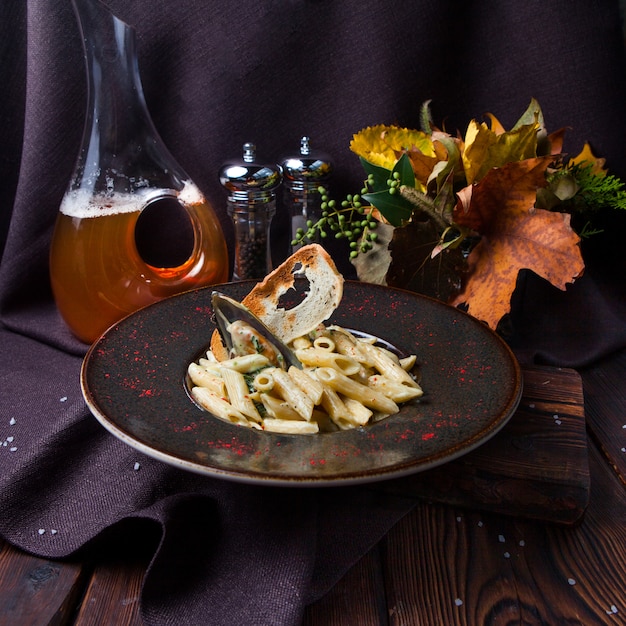 Some macaroni in a black plate on black background with decorations, high angle view.