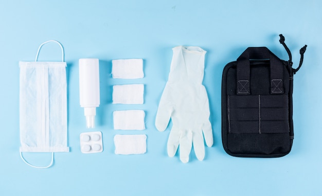 無料写真 ハンドバッグ、マスク、包帯、スプレーでいくつかの医療用手袋は、明るいシアンの背景、上面に並んでいます。