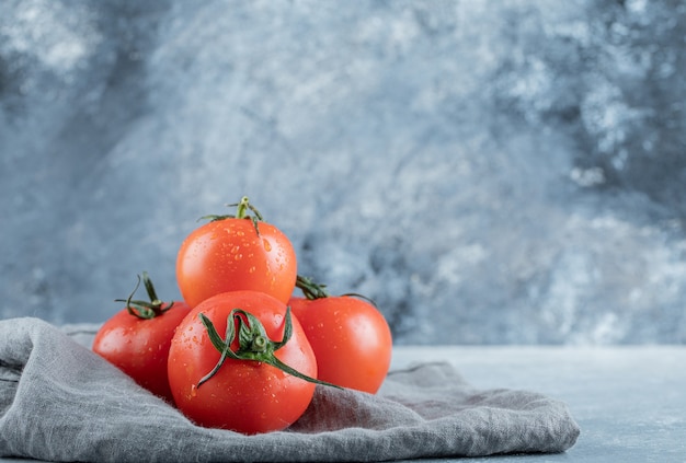 Бесплатное фото Некоторые из свежих помидоров на серой скатерти.