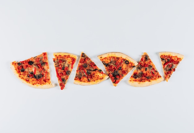 Some slices of pizza on light blue stucco background, top view.