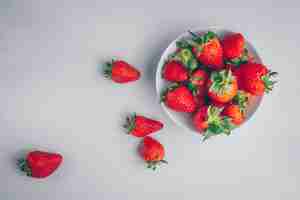 Free photo some strawberries in a bowl on white background, top view.