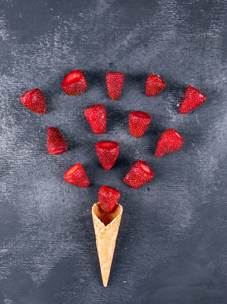 Free photo some strawberries forming an ice cream shape on dark table, top view.