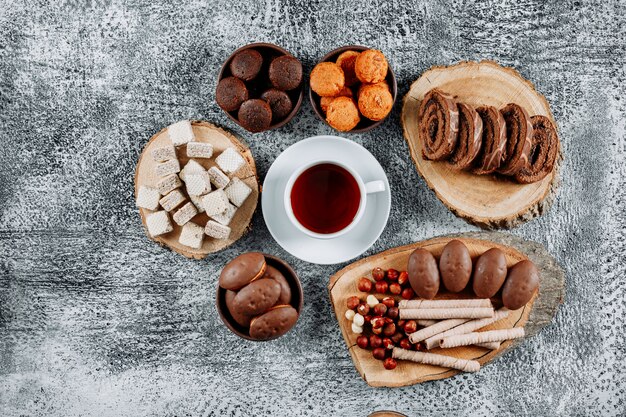 Some tea with waffles and cakes in plates and cutting board on light textured