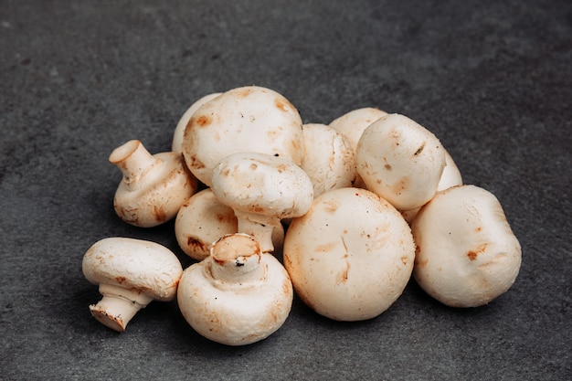 Some white mushrooms on gray textured background, high angle view.