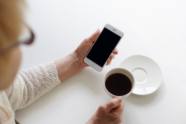 誰かがコーヒーを飲みながら電話を使用しています