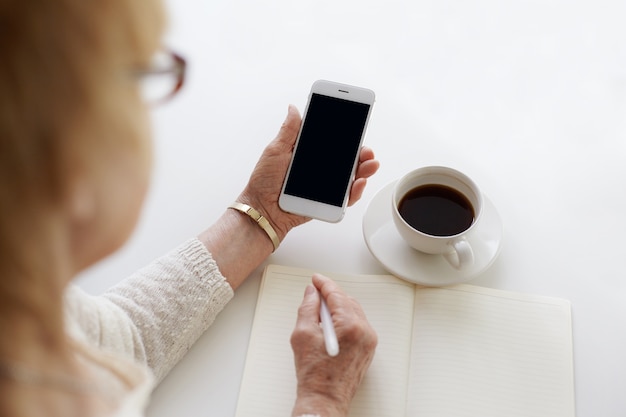 誰かがコーヒーを飲みながら電話を使用しています