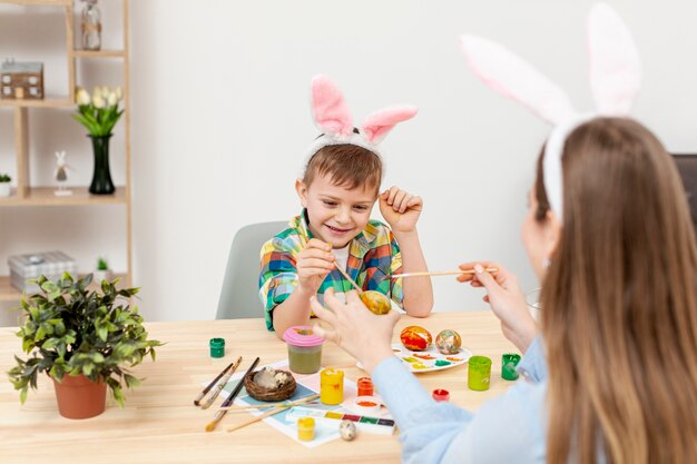 Son enjoying to paint eggs with his mom