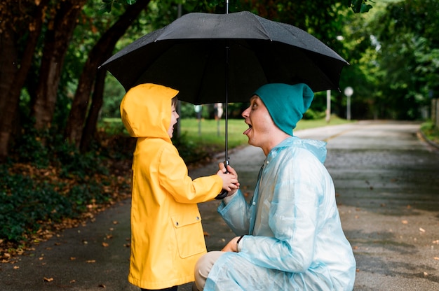 Son and father looking at each other under an umbrella