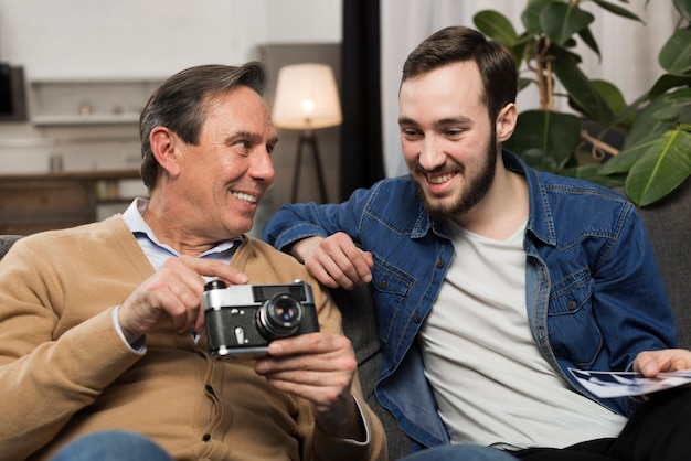 Son and father looking at photos in living room