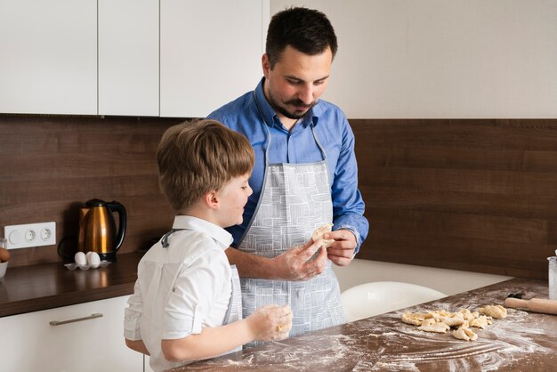 Son and father making dough together