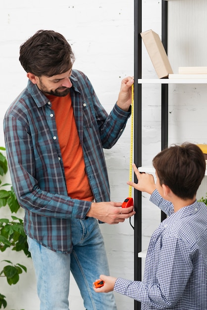 Son and father measuring a self