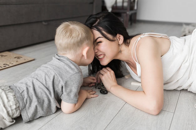 Son and his mother lying on hardwood floor rubbing their nose