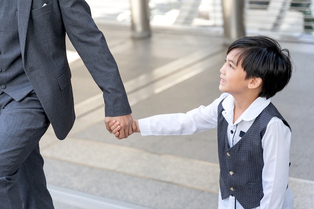 Son holding father's hand on business district urban