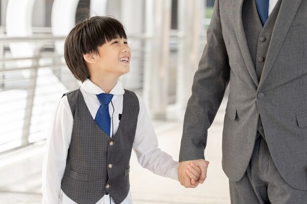 Son holding father's hand on business district urban