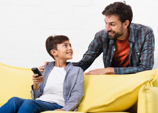 Son holding remote control and looking at his father