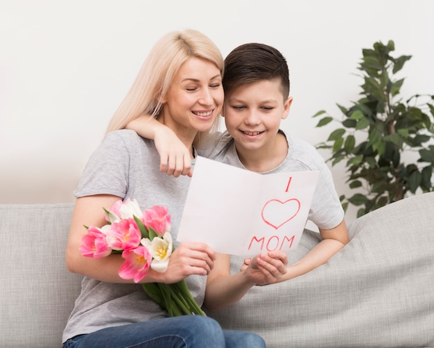 Son and mother on couch reading card