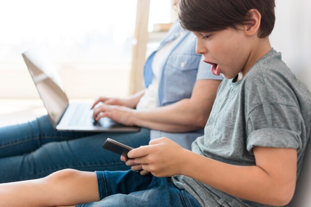 Son playing on smartphone next to mom