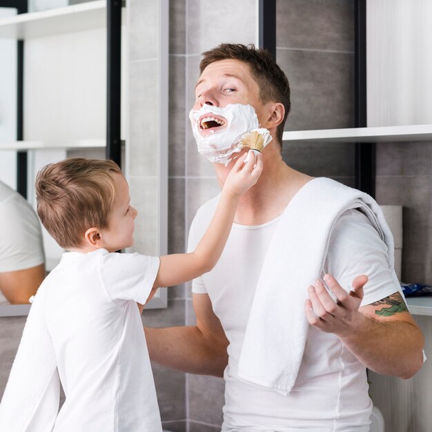 Son shaving his father's cheeks and chin in the bathroom