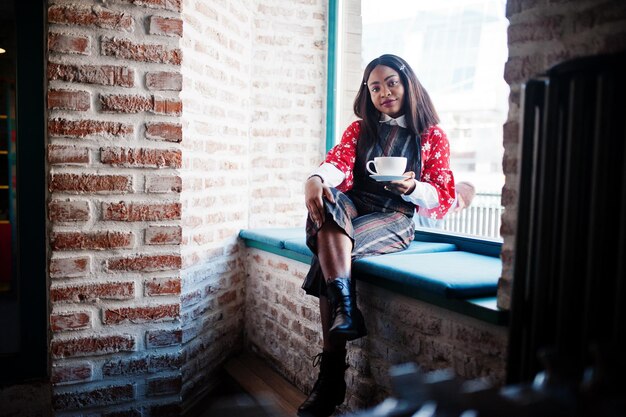 Sonfident young african american woman in smart casual wear at cafe with cup of hot drink in hand