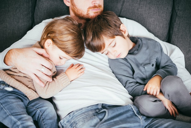 Foto gratuita figli che fanno un pisolino sul petto del padre