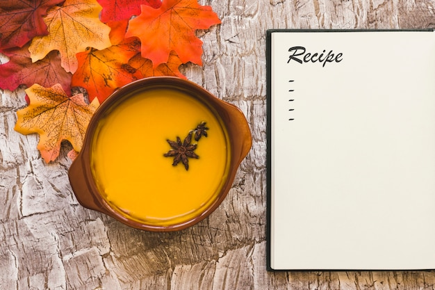 Soup and leaves near notebook with recipe
