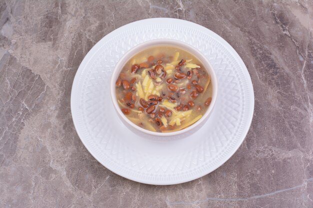 Soup with brown beans and spaghetties in a white ceramic cup