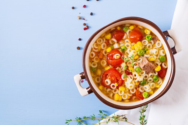 青いテーブルの上のボウルに小さなパスタ、野菜、肉の部分のスープ。イタリア料理。