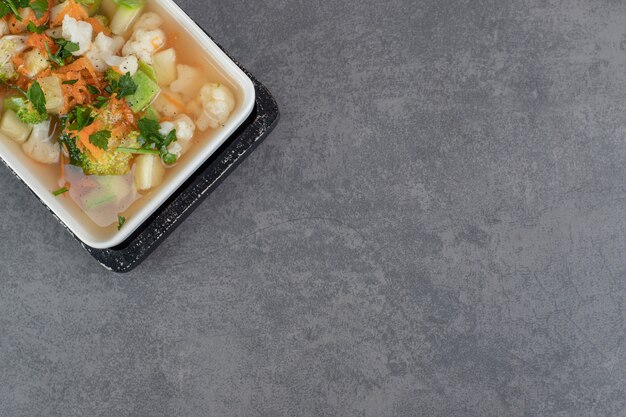 Бесплатное фото Суп с различными овощными ломтиками на белой тарелке. фото высокого качества
