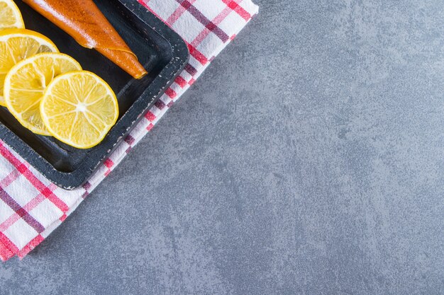 Sour and slice lemon on a board on the tea towel on the marble surface