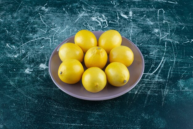 Sour yellow lemons on purple plate. 