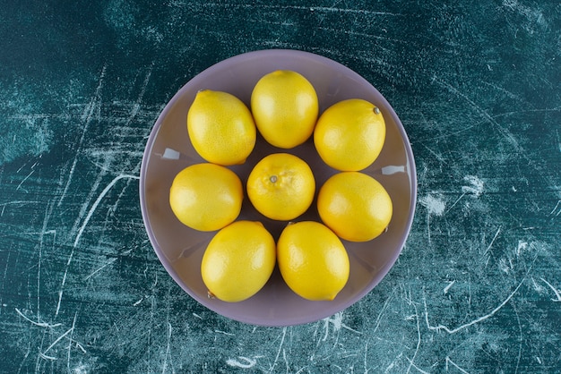 Free photo sour yellow lemons on purple plate.