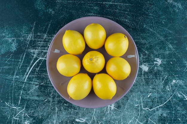 Sour yellow lemons on purple plate. 