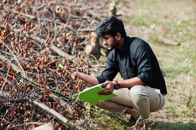 ファームガーデンで伐採された木をクリップボードで検査する南アジアの農業者農家農業生産コンセプト