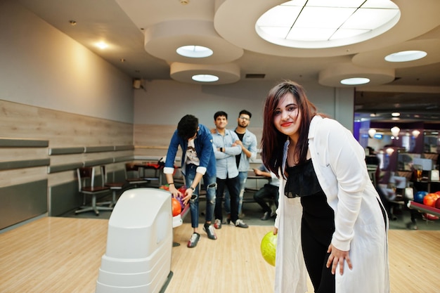 South asian woman standing at bowling alley with ball on hands Girl is preparing for a throw