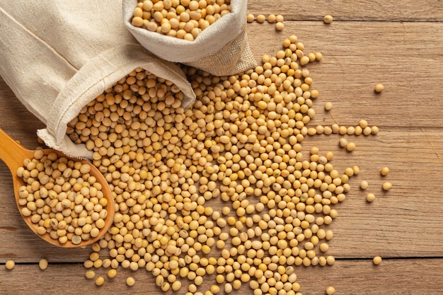 Soybean seeds on wooden floor and hemp sacks Food nutrition concept.