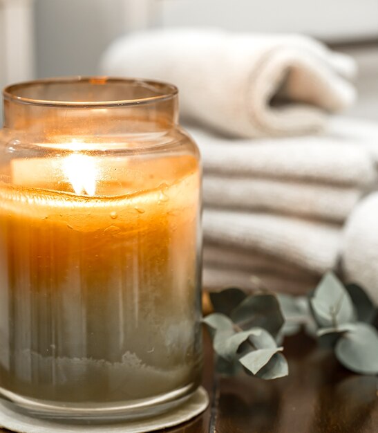 Spa composition with burning candle, bath towels close up. Aromatherapy concept.