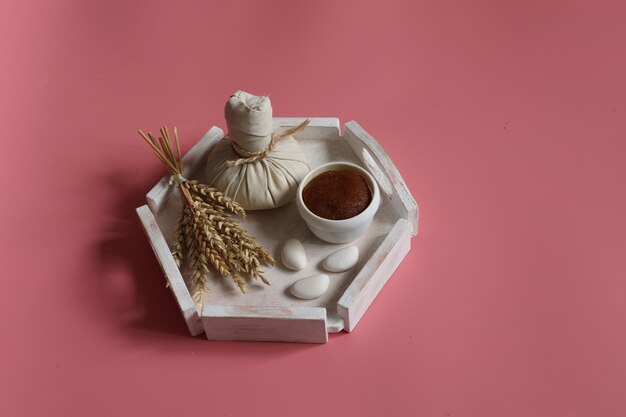 Spa composition with herbal bag and natural scrub on a pink background