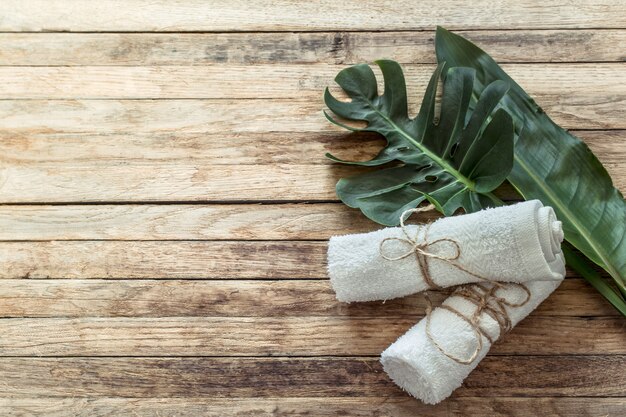 Spa composition with towels and tropical leaf on a wooden wall.