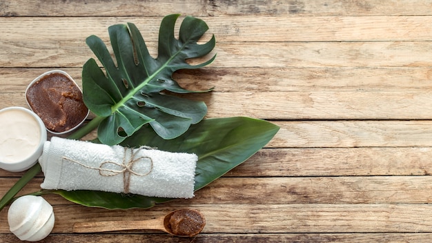 Spa composition with towels and tropical leaf on a wooden wall.