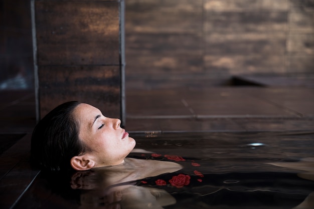 Concetto della stazione termale con la donna che si distende in acqua