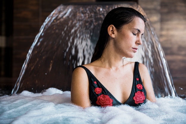 Concetto della stazione termale con la donna che si distende in acqua