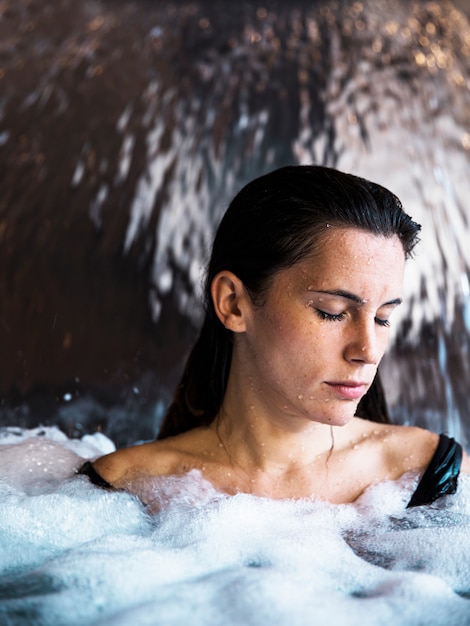 Concetto della stazione termale con la donna che si distende in acqua