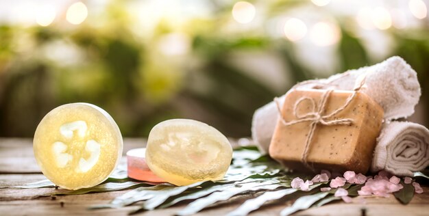 Spa handmade soap and a towel, the composition of the tropical leaves wooden background