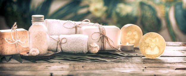 Спа-мыло ручной работы с белыми полотенцами и морской солью, композиция из тропических листьев со свечой, деревянный фон