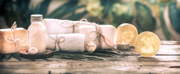 Spa handmade soap with white towels and sea salt, the composition of the tropical leaves with a candle, wooden background