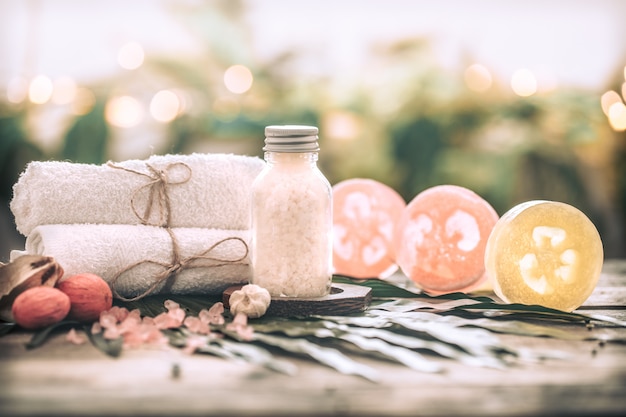 Spa handmade soap with white towels and sea salt, composition on tropical leaves, wooden background