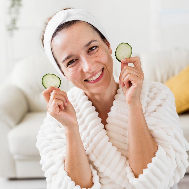 Foto gratuita spa a casa donna sorridente che tiene le fette di cetriolo