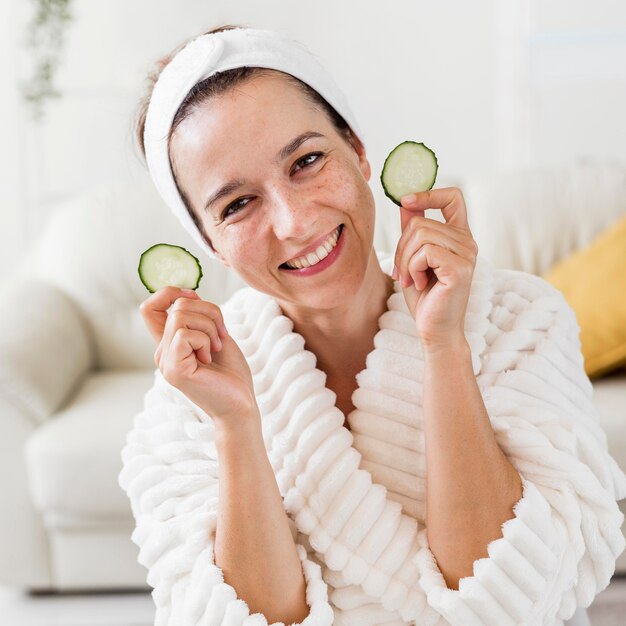 Free photo spa at home smiley woman holding slices of cucumber